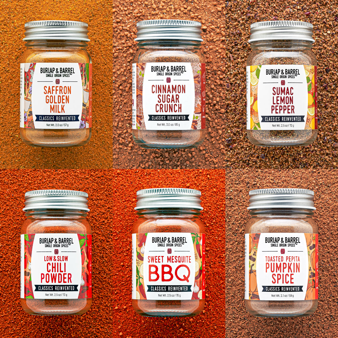 Six jars of Burlap & Barrel spices on a textured brown background