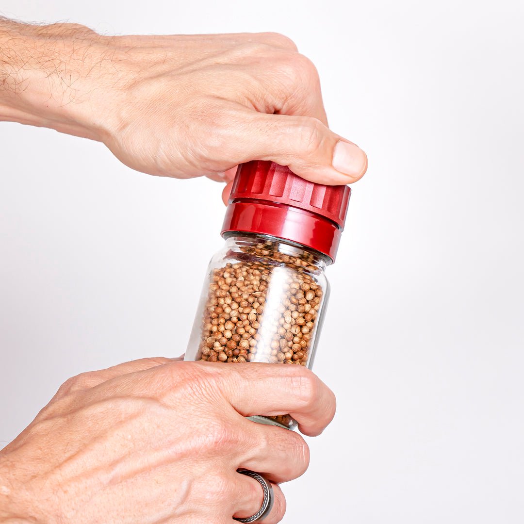 A closeup of two hands adjusting the coarseness of the grinding mechanism on a Burlap & Barrel removable grinder-top.