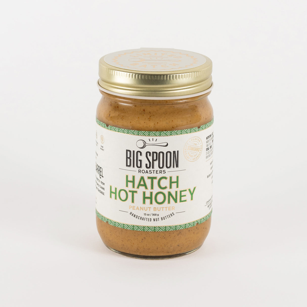 A jar of Big Spoon Roasters Hatch Hot Honey in garlic butter flavor, featuring a white label with green text and a gold metal lid, set against a plain white background.
