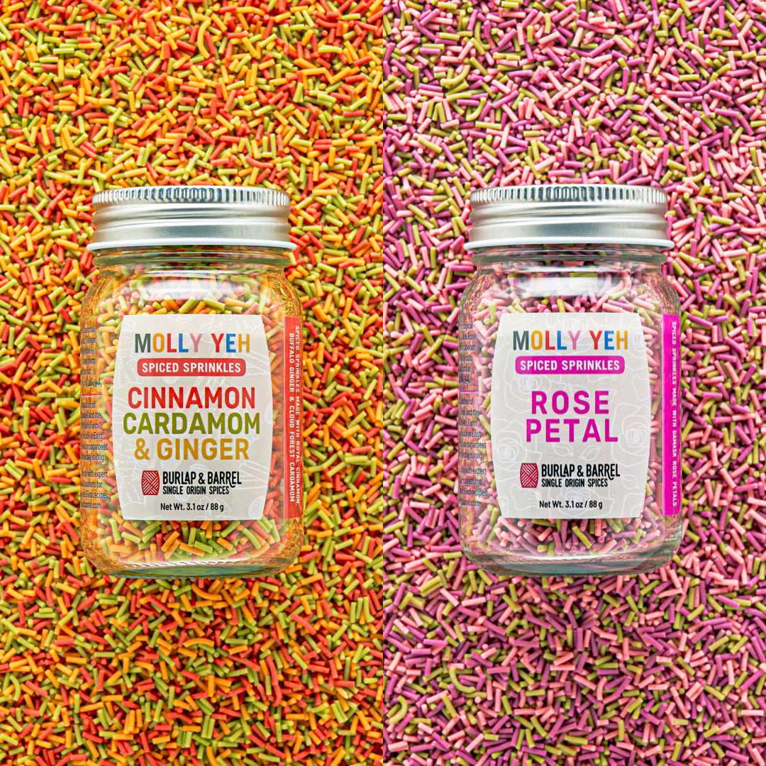 Two jars of Molly Yeh spiced sprinkles on a colorful sprinkle background.