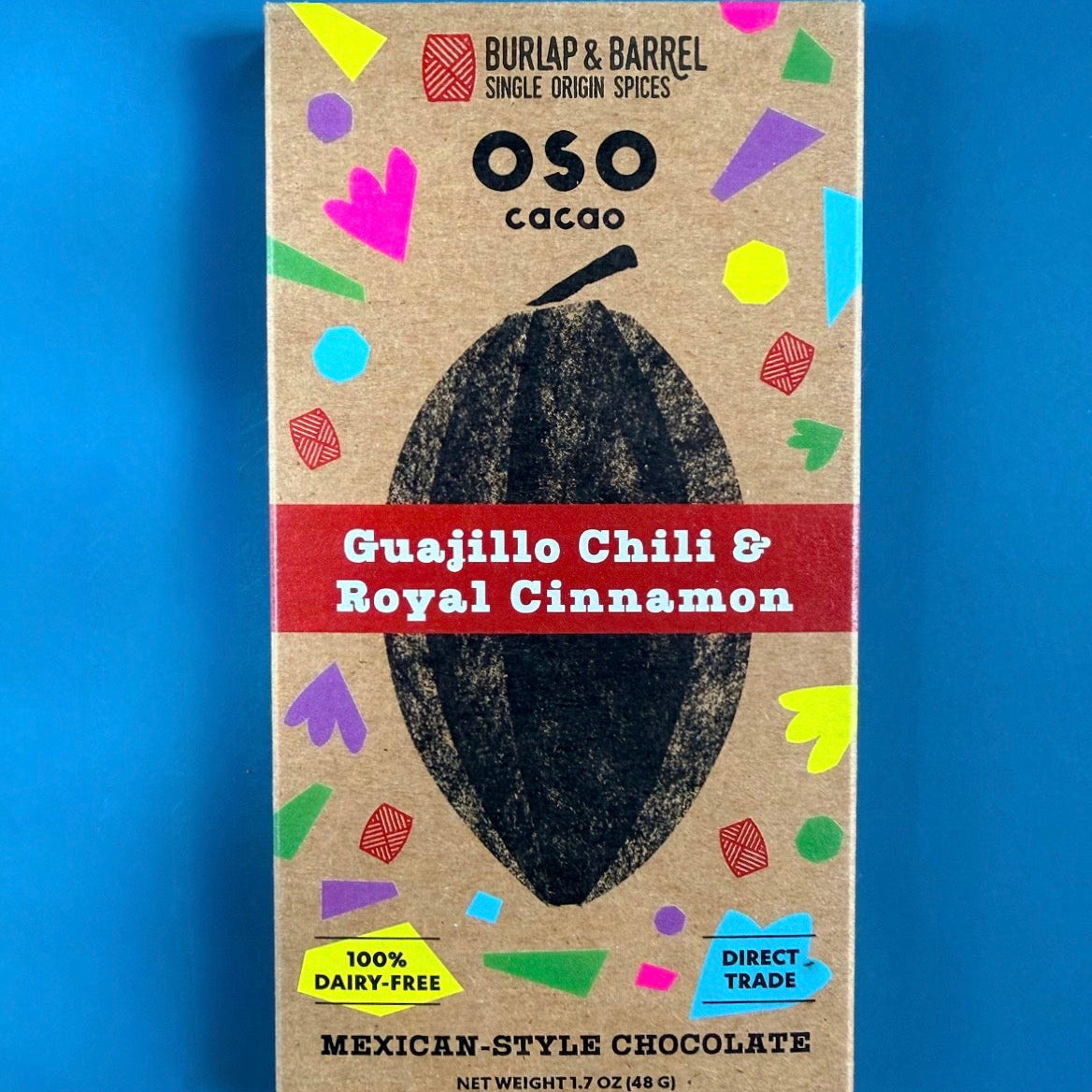 Oso Cacao Guajillo Chili & Royal Cinnamon chocolate packaging on a blue background.