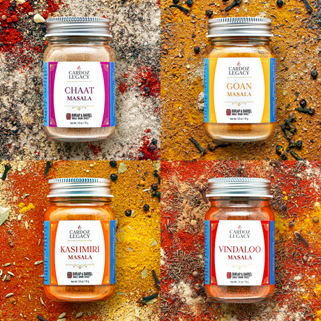 Four jars of Cardoz Legacy spices on a textured surface with spices around them.