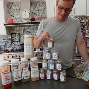 Man in a kitchen with various spice jars on the counter