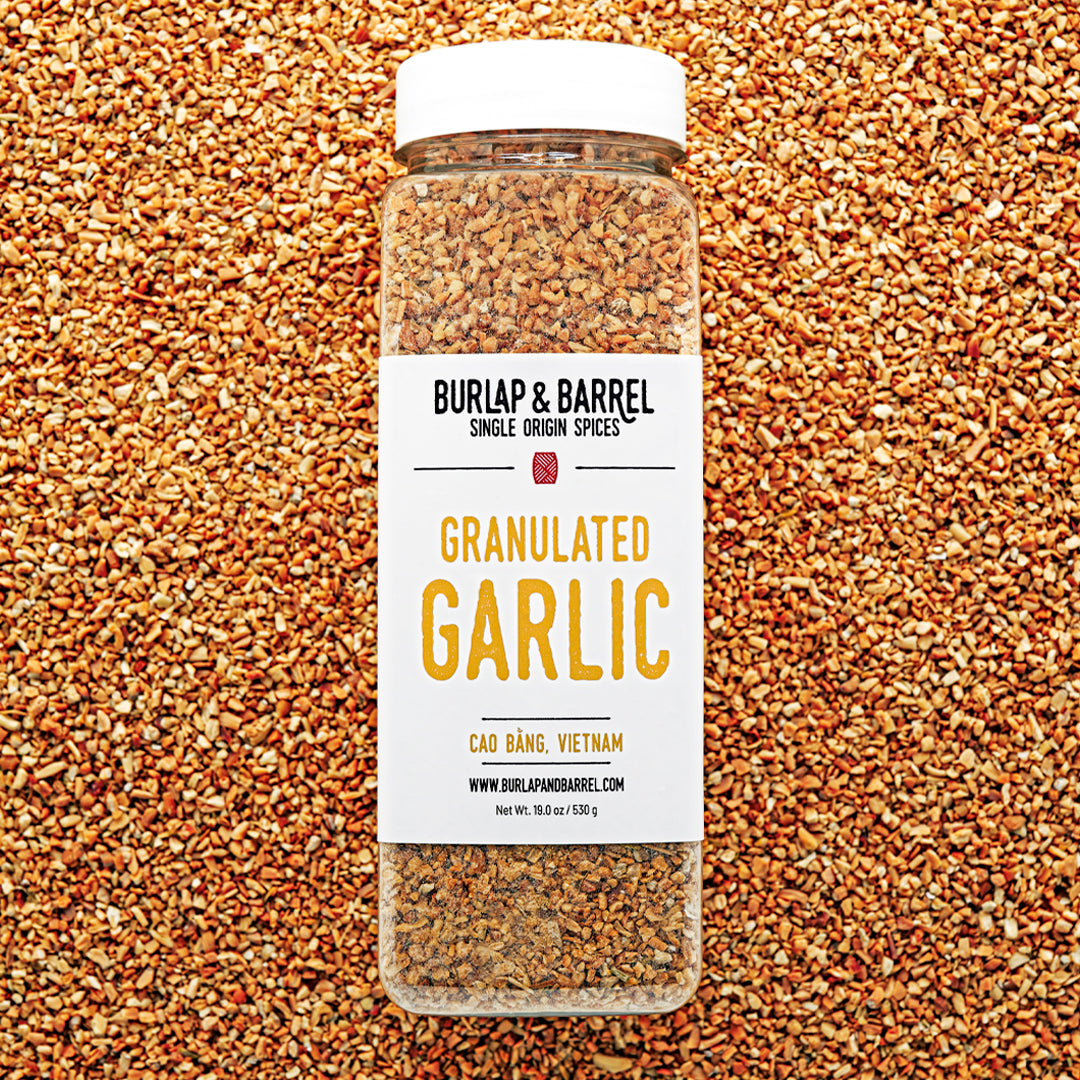 Jar of granulated garlic from Burlap & Barrel on a bed of granulated garlic.