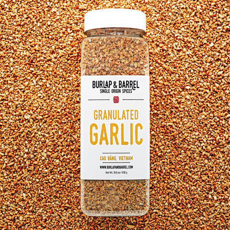 Jar of granulated garlic from Burlap & Barrel on a bed of granulated garlic.