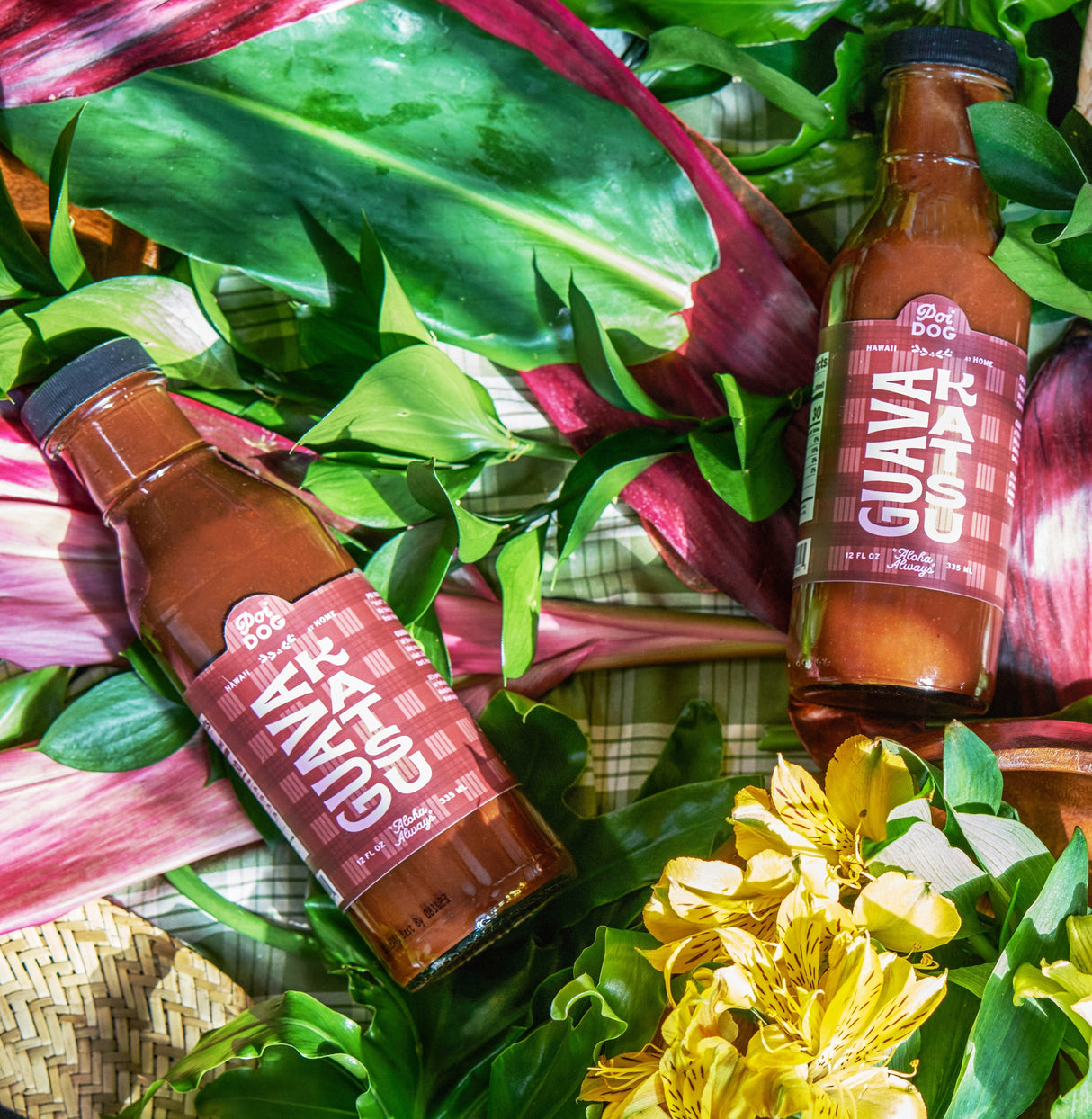 Two bottles of Guava Katsu Sauce on a leafy green background with flowers.