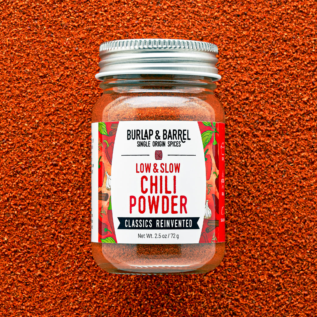 Jar of Burlap & Barrel Low & Slow Chili Powder on a textured brown background