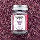 A jar of Purple Dulse Flakes by Burlap & Barrel, sustainably hand-harvested from the Bay of Fundy, Canada, displayed on a background of dulse flakes.