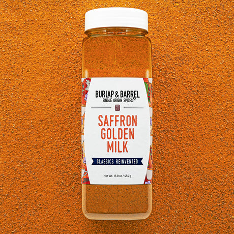 Container of Burlap & Barrel Saffron Golden Milk spice blend on an orange background