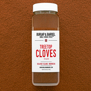 Container of Burlap & Barrel Treetop Cloves on a brown background