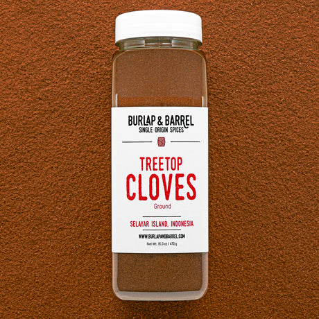Container of Burlap & Barrel Treetop Cloves on a brown background