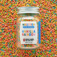 Jar of Molly Yeh & Burlap & Barrel Spiced Sprinkles with colorful sprinkles in the background